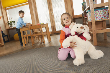 Deutschland, Junge (4-5) und Mädchen (3-4) im Kinderzimmer, Mädchen hält Teddy, Porträt - RNF00206