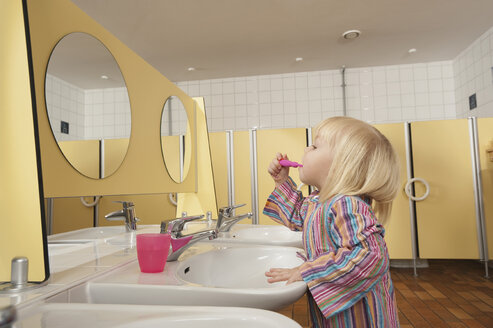 Deutschland, Mädchen (3-4) auf der Toilette beim Zähneputzen, Seitenansicht, Porträt - RNF00197