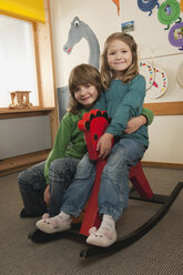 Germany, Nursery, Two girls (4-5) (6-7) on rocking horse - RNF00189