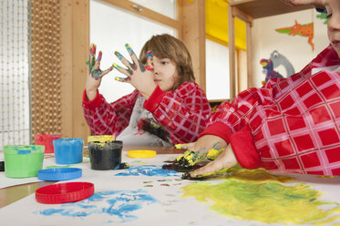 Germany, Two boys (3-4), (6-7) fingerpainting in nursery - RNF00179