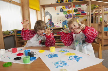 Deutschland, Zwei Jungen (3-4), (6-7) beim Fingermalen im Kinderzimmer, Hände zeigen, lächelnd, Porträt - RNF00177