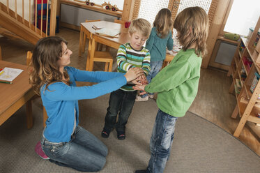 Germany, Nursery, Female nursery teacher and children playing together - RNF00163