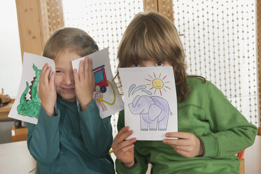 Deutschland, Junge (6-7) und Mädchen (4-5) im Kinderzimmer, Gesichter mit Bildern bedeckt, lächelnd, Porträt - RNF00161