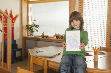 Germany, Boy (6-7) in nursery hoding painting, smiling, portrait - RNF00160