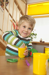 Deutschland, Junge (3-4) im Kinderzimmer beim Spielen mit Knetmasse, lächelnd, Porträt - RNF00146