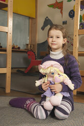 Deutschland, Portrait eines Mädchens (4-5) im Kinderzimmer mit Puppe - RNF00126