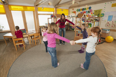 Deutschland, Kindergarten, Kindergärtnerin und tanzende Kinder - RNF00119