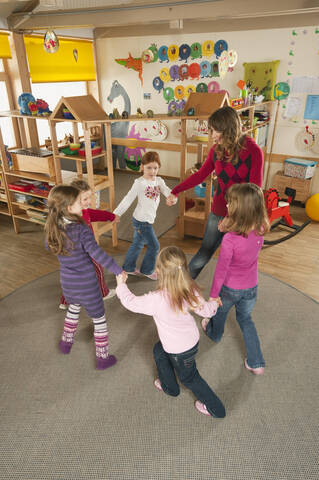 Germany, Nursery, Female nursery teacher and children dancing stock photo