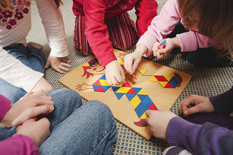 Deutschland, Fünf Kinder spielen gemeinsam ein Lernspiel, Nahaufnahme, Mittelteil, lizenzfreies Stockfoto