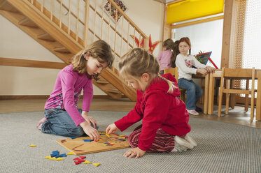 Deutschland, Kinder im Kindergarten, Zwei Mädchen (3-4), (4-5) im Vordergrund spielen ein Lernspiel - RNF00115