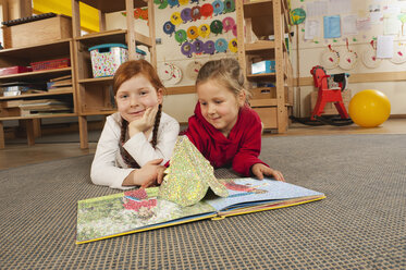 Deutschland, Zwei Mädchen (4-5), (6-7) im Kinderzimmer beim Lesen eines Buches, Porträt - RNF00098