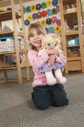 Deutschland, Mädchen (4-5) im Kinderzimmer mit Puppe, lachend, Porträt - RNF00089