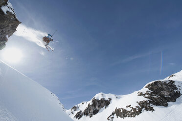 Austria, Arlberg, Man skiing downhill, doing jump, low angle view - MIRF00031