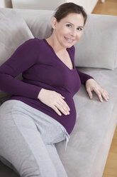 Pregnant woman lying on couch, smiling, portrait - MAEF02196