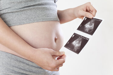 Schwangere Frau hält Ultraschallbilder, Mittelteil - MAEF02067