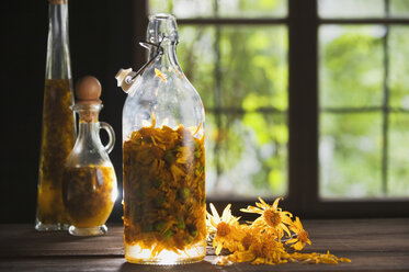 Österreich, Salzburger Land, Arnikablüte in Flasche auf Tisch - HHF03162