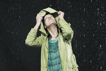 Woman holding hood in rain, looking up. - FMKF00087