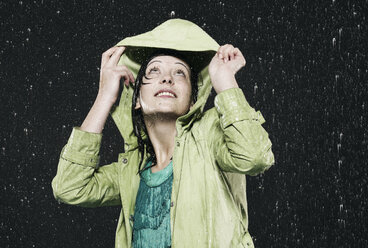 Woman holding hood in rain, looking up - FMKF00086