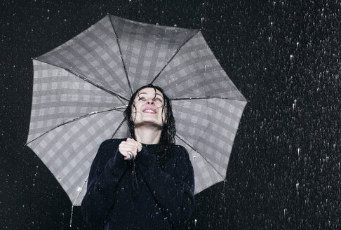 Frau steht im Regen und hält einen Regenschirm. - FMKF00054