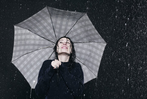 Woman standing in rain, holding umbrella. - FMKF00054