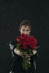 Man holding bunch of flowers, standing in rain. - FMKF00046