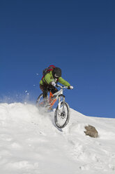 Deutschland, Bayern, Kampenwand, Mann beim Mountainbiken im Schnee - FFF01108