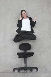 Geschäftsfrau, die ein Mobiltelefon benutzt, das über einem Stuhl schwebt, Blick von oben - BAEF00075
