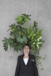 Geschäftsfrau mit Blattpflanzen auf dem Kopf, lächelnd, Porträt, Draufsicht - BAEF00068