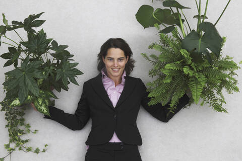 Geschäftsfrau mit Blattpflanzen in der Hand, Porträt, Ansicht von oben, lizenzfreies Stockfoto