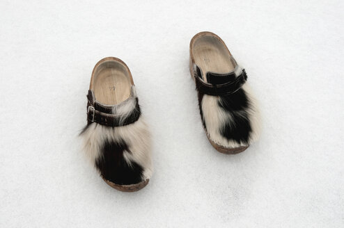 Ein Paar Holzschuhe mit Kuhfell im Schnee, Winter. - AWDF00501