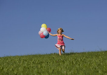 Austria, Mondsee, Girl (4-5) running through meadow holding balloons - WWF01258