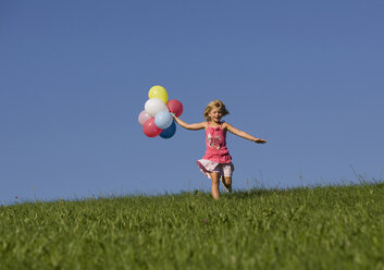 Österreich, Mondsee, Mädchen (4-5) läuft mit Luftballons durch eine Wiese - WWF01258