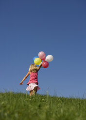 Austria, Mondsee, Girl (4-5) running through meadow holding balloons - WWF01257