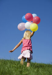 Austria, Mondsee, Girl (4-5) running through meadow holding balloons - WWF01256