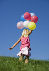 Österreich, Mondsee, Mädchen (4-5) läuft mit Luftballons durch eine Wiese - WWF01256