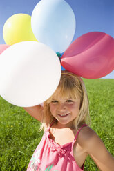 Österreich, Mondsee, Mädchen (4-5) stehend auf Wiese mit Luftballons, lächelnd, Porträt - WWF01254