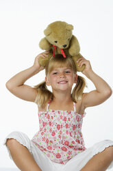 Mädchen (4-5) spielt mit Teddybär, lächelnd - WWF01229