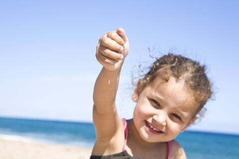 France, Corsica, Girl (2-3) holding sand, smiling, portrait stock photo