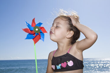 Frankreich, Korsika, Mädchen (2-3) bläst Papierwindmühle am Strand - SSF00047