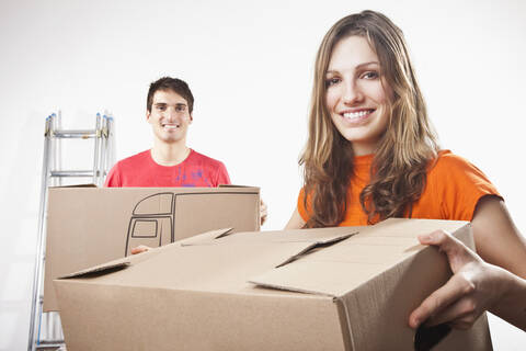 Young couple carrying cardboard boxes, smiling, portrait stock photo