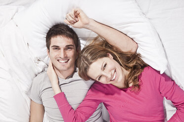 Junges Paar auf dem Bett liegend, lächelnd, Porträt - SSF00020