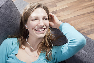 Woman relaxing on couch and listening music, smiling - SSF00014