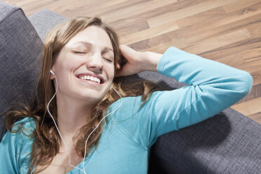 Woman relaxing on couch and listening music, smiling - SSF00013
