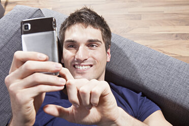 Man text messaging on mobile phone, smiling, close-up - SSF00012