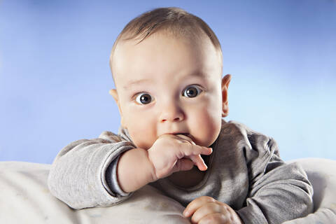 Baby-Junge (6-11 Monate) mit Finger im Mund, Nahaufnahme, Porträt, lizenzfreies Stockfoto