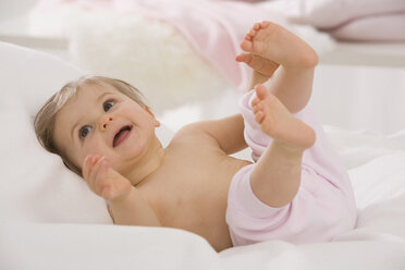 Baby-Mädchen (6-11 Monate) auf dem Rücken liegend, lächelnd, wegschauend - SMOF00439