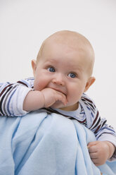 Baby boy (6-11 months) with finger in mouth, looking away - SMOF00415