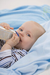 Baby boy (6-11 months) holding baby bottle, portrait - SMOF00411