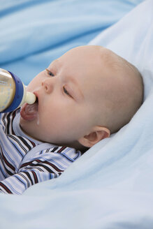 Baby boy (6-11 months) holding baby bottle, mouth open - SMOF00409