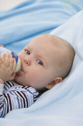 Baby boy (6-11 months) holding baby bottle, portrait - SMOF00408